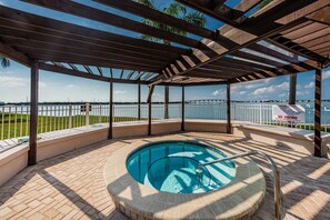 A covered outdoor swimming pool with a view of the water and a white fence.