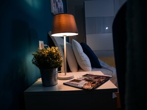 Relax in a cozy bedroom with a bedside table, floor lamp, and plush pillows.