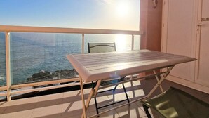 Un balcón con una mesa y una silla, con vista al mar.