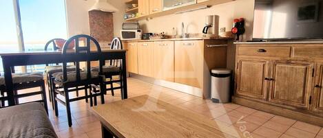 A modern kitchen with wooden cabinets, a dining table with chairs, and a large window providing a view of the outdoors.