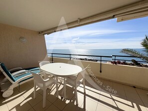 A balcony with a white table and chairs, a view of the sea, and a railing. - T2 + COIN CHAMBRE, TERRASSE 1ERE LIGNE MER (Sète)