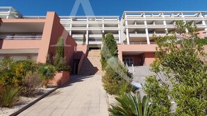 Un edificio moderno con una escalera central que lleva a una zona cubierta, rodeada de zonas verdes ajardinadas.
