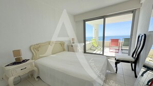 Un dormitorio con una cama grande, una mesita de noche, una silla y vistas al balcón.