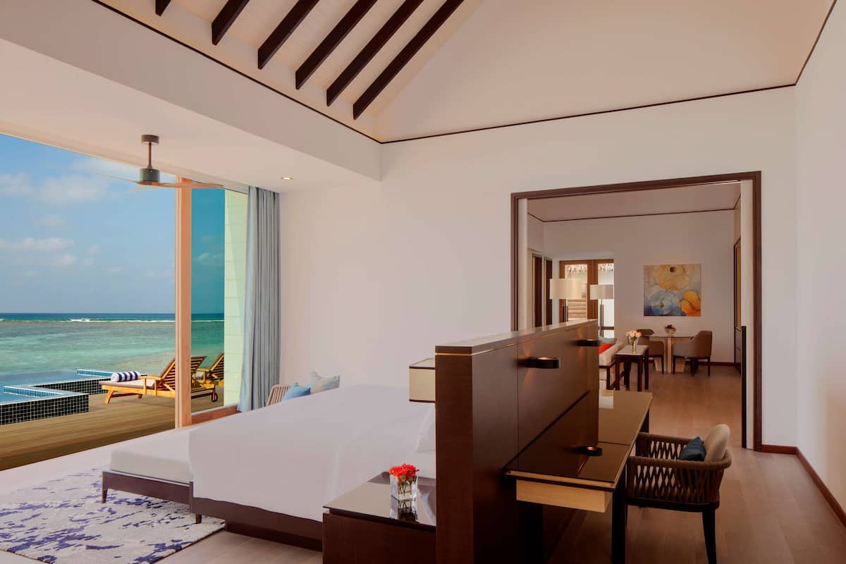 Habitación de hotel moderna con una cama grande, un escritorio y vista al océano.