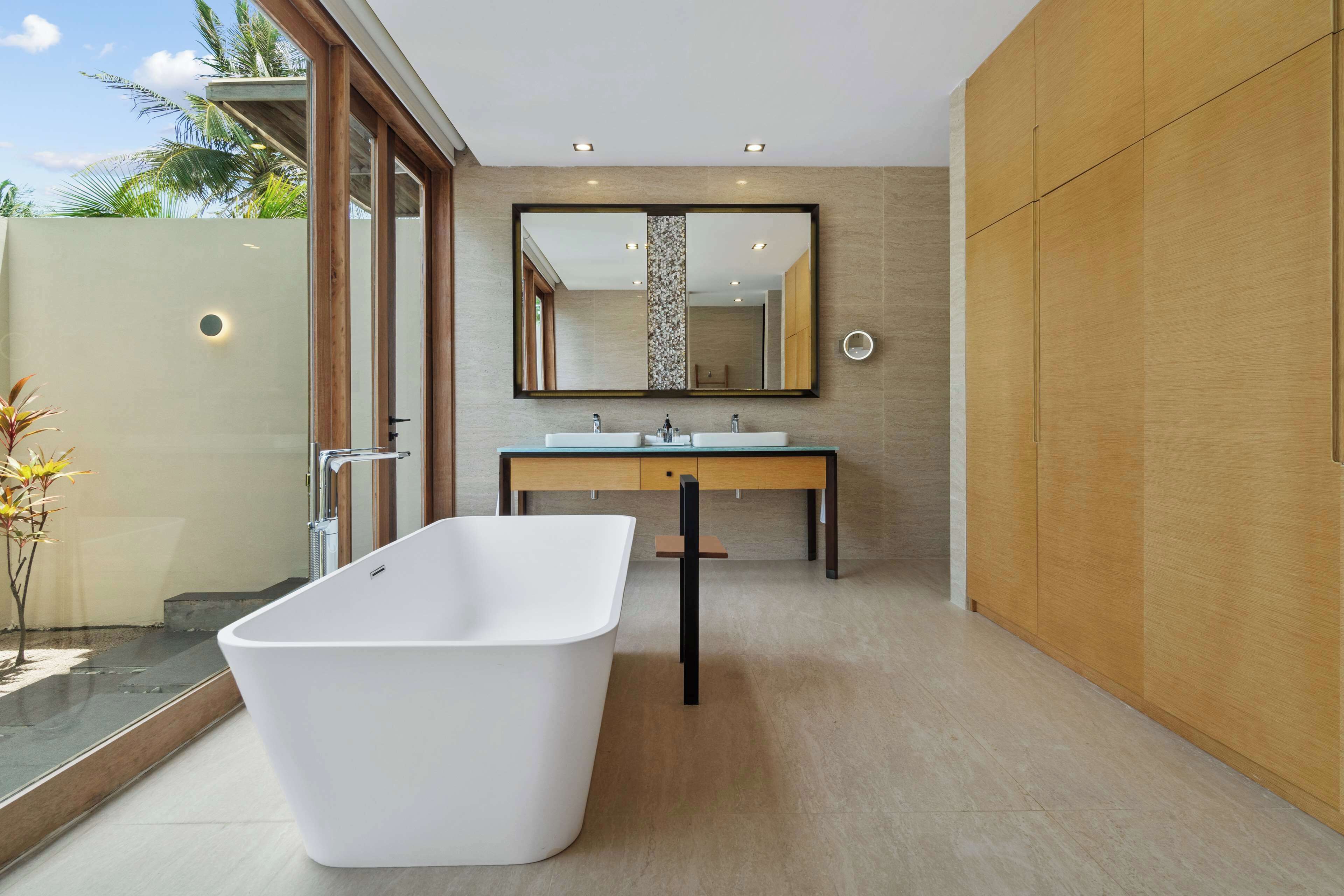 A modern bathroom with a freestanding bathtub, a large mirror, and a wooden vanity.