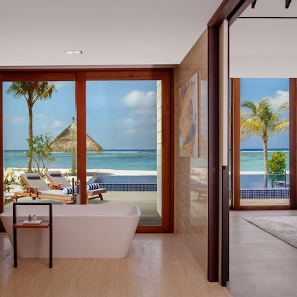 A modern hotel room with a large window offering a view of the beach and ocean.