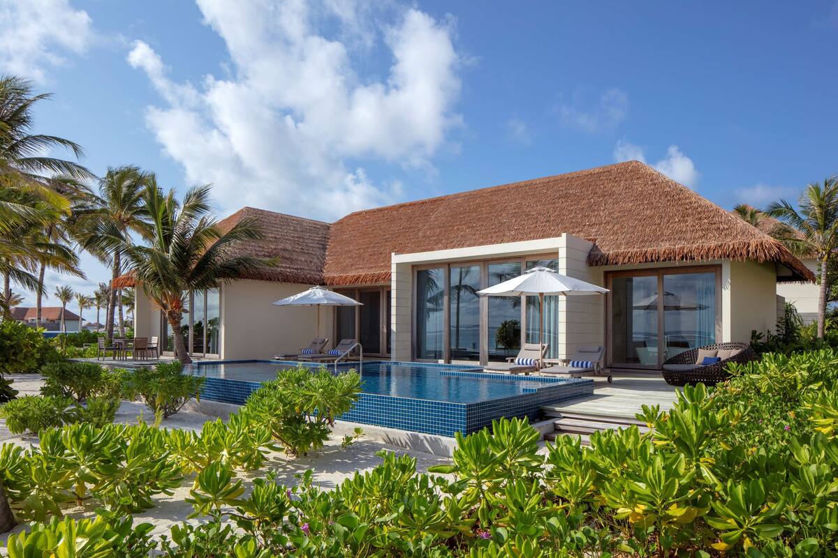 Un resort con piscina, sillas de descanso y palmeras.