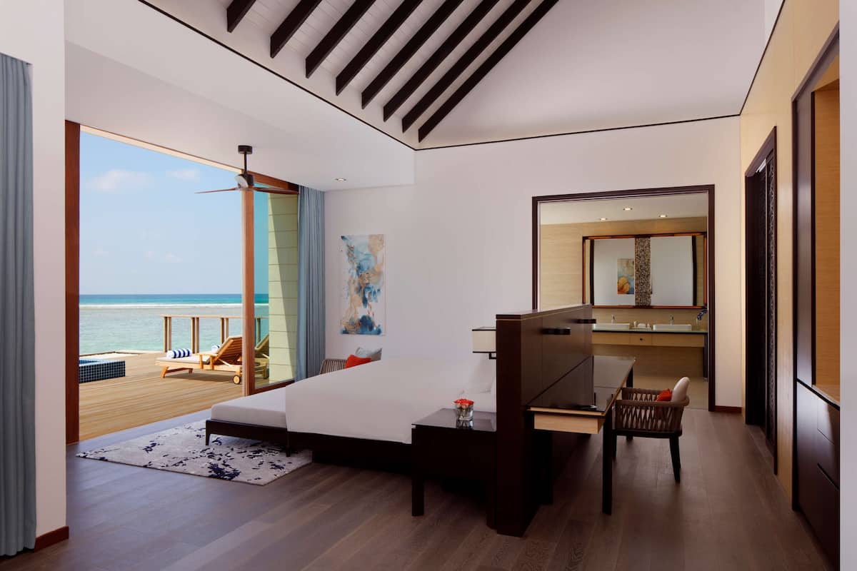 Una habitación de hotel moderna con una cama grande, un escritorio y vistas al océano.