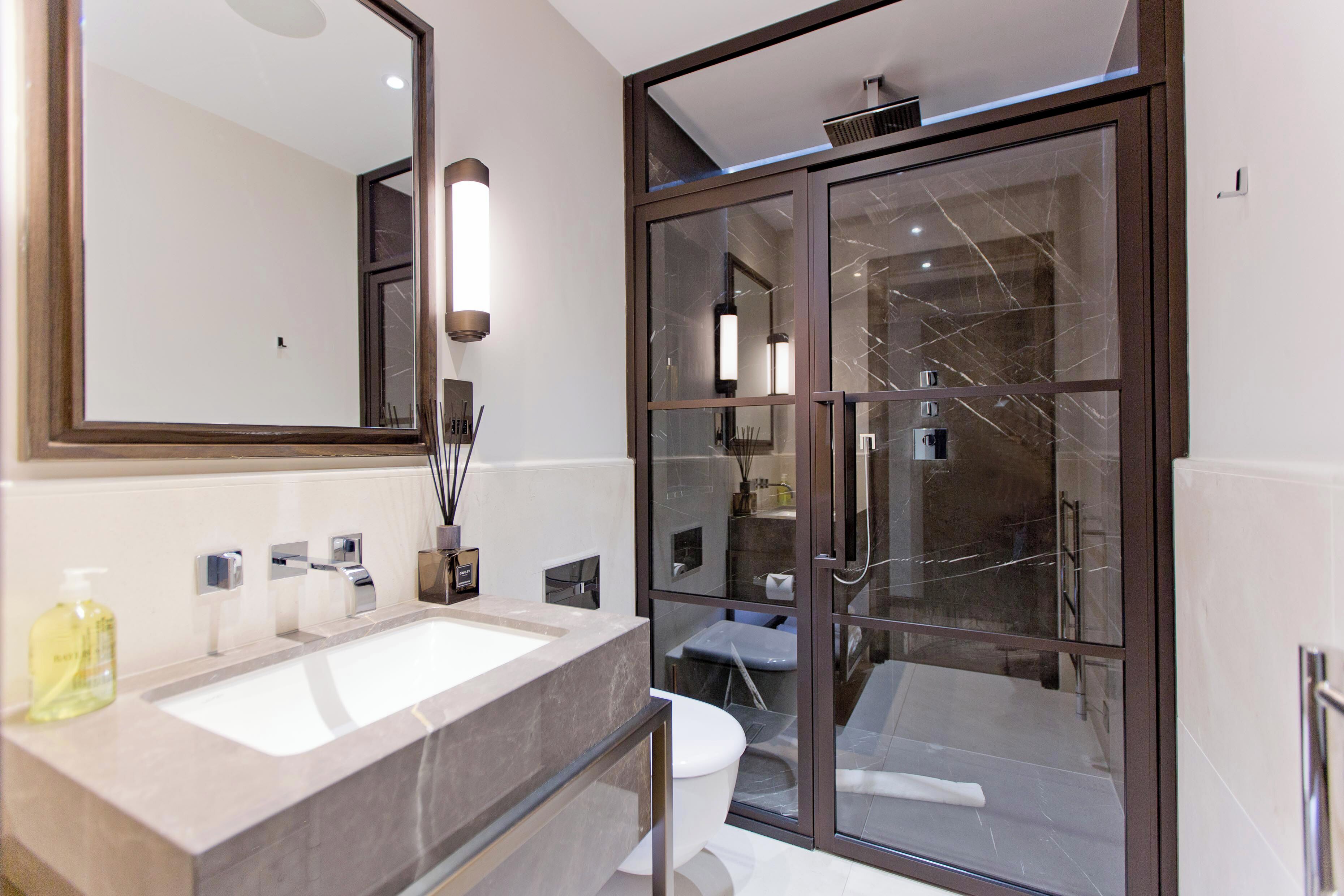 A modern bathroom with a large mirror, dual sinks, and a glass-enclosed shower area.