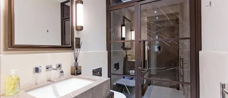 A modern bathroom with a large mirror, dual sinks, and a glass-enclosed shower area.