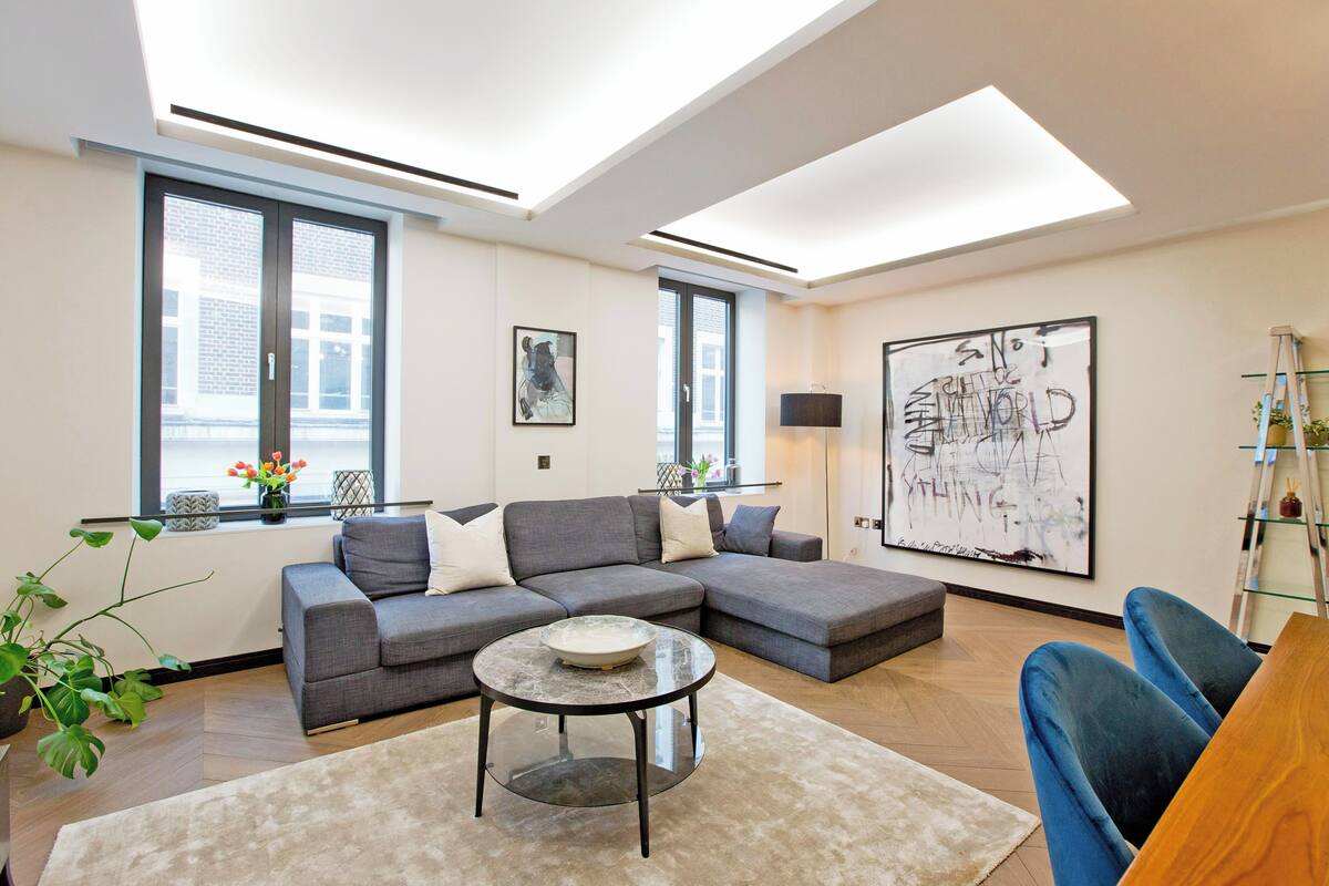 Ein modernes Wohnzimmer mit einer Eckcouch, einem runden Couchtisch und einem großen abstrakten Gemälde.