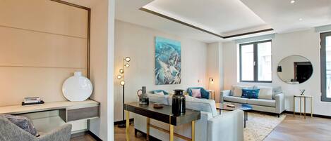 A modern living room with a sofa, a coffee table, and a desk with a lamp.