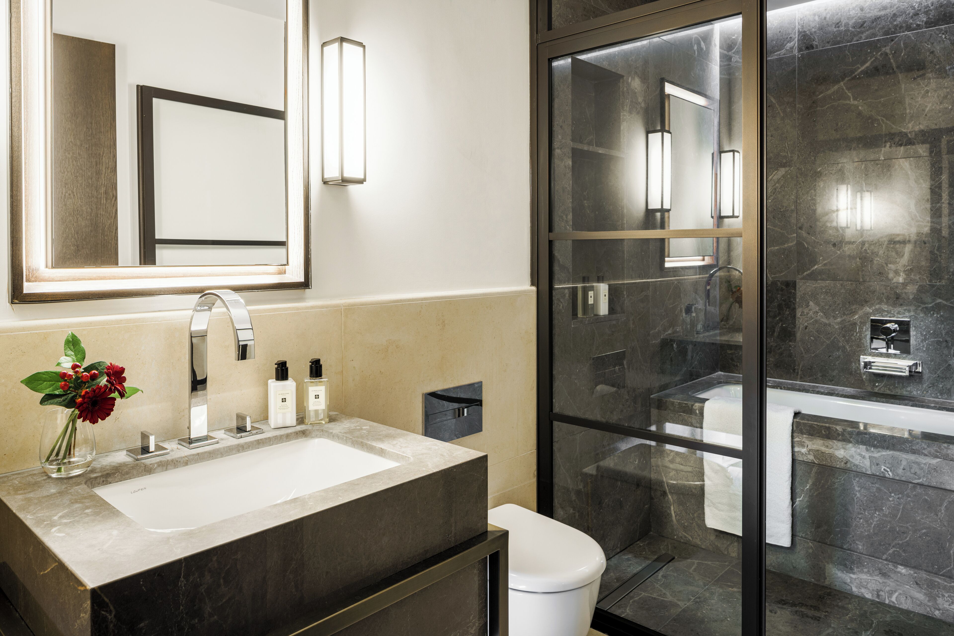 A modern bathroom with a large mirror, a sink, and a glass-enclosed shower.