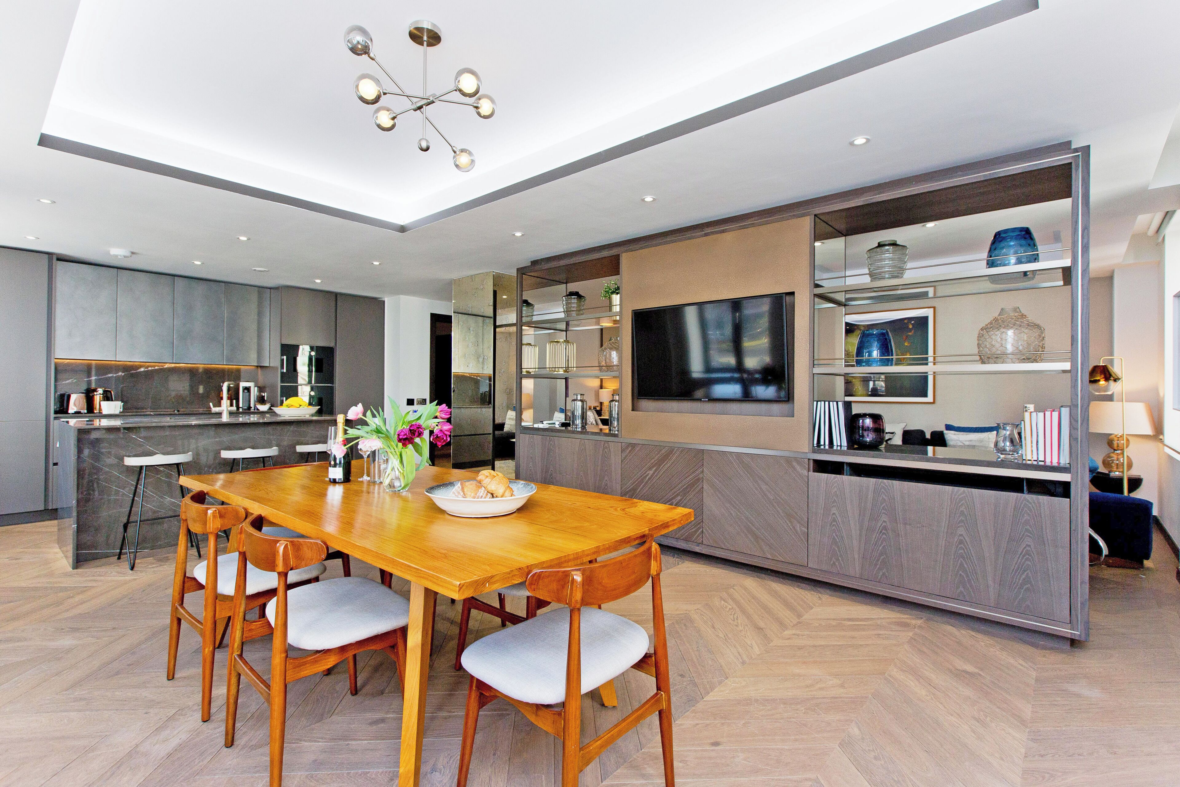 A modern kitchen with a wooden dining table, built-in appliances, and a large island.