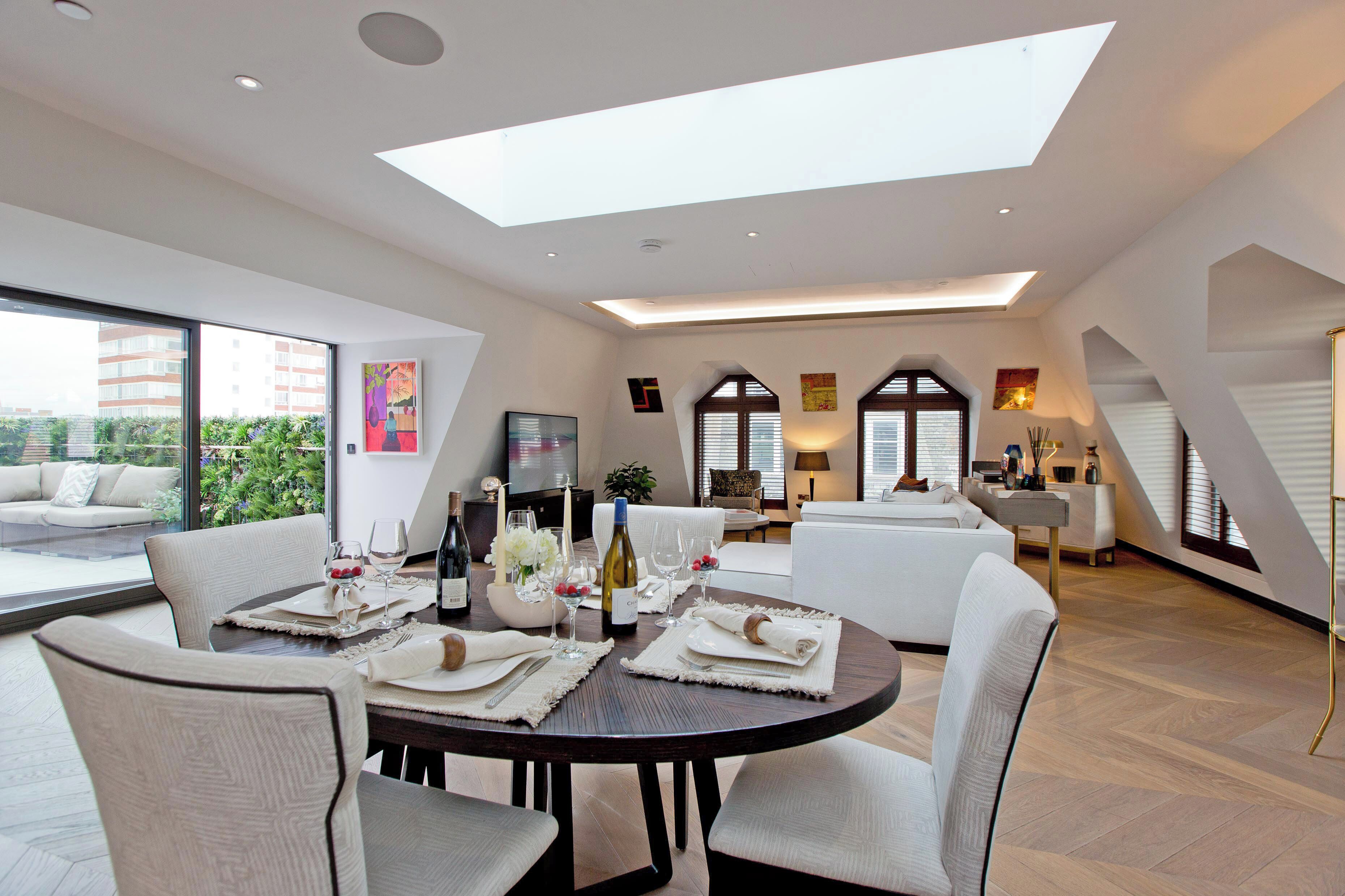 A modern dining area with a round table set for six, surrounded by six chairs.