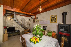 A dining area with a table set for two, a stone wall, a staircase, and a fireplace. - Holiday house Pivcevi (Podgora)