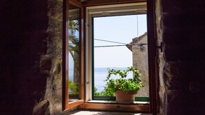 A window with a view of the sea, a potted plant, and a stone wall. - Holiday house Pivcevi (Podgora)