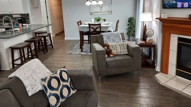 A modern living room with a fireplace, a dining area, and a kitchen. - Luxury! 2 king beds and 2 full bathrooms (Manteno)