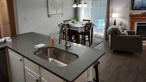 A modern kitchen with a large island, dining area, and a cozy living space with a fireplace. - Luxury! 2 king beds and 2 full bathrooms (Manteno)