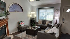 A living room with a fireplace, a sofa, a coffee table, and a television. - Luxury! 2 king beds and 2 full bathrooms (Manteno)