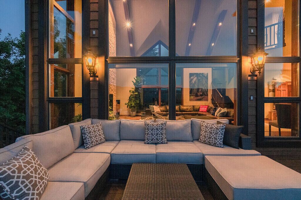 Un interior moderno con un sofá seccional grande, una mesa de centro tejida y vistas a una zona de estar acogedora con chimenea.