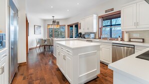 Une cuisine moderne avec des meubles blancs, un grand îlot central et un coin repas avec des chaises.