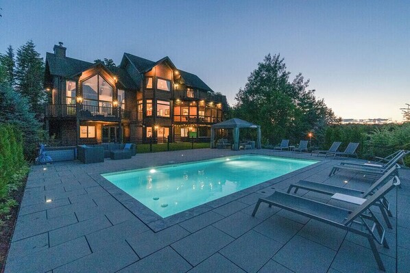 A large, multi-story house with a swimming pool and outdoor seating area. - Spectacular home with breathtaking views of Mont-Tremblant, minutes from resort. (Mont-Tremblant)