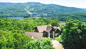 Un chalet offrant une vue sur la montagne, entouré d’une forêt dense, avec un lac en arrière-plan.