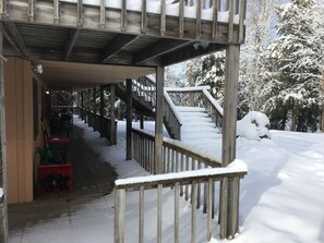 Ein hölzerner, überdachter Gang führt zu einem Gebäude mit einer schneebedeckten Treppe.