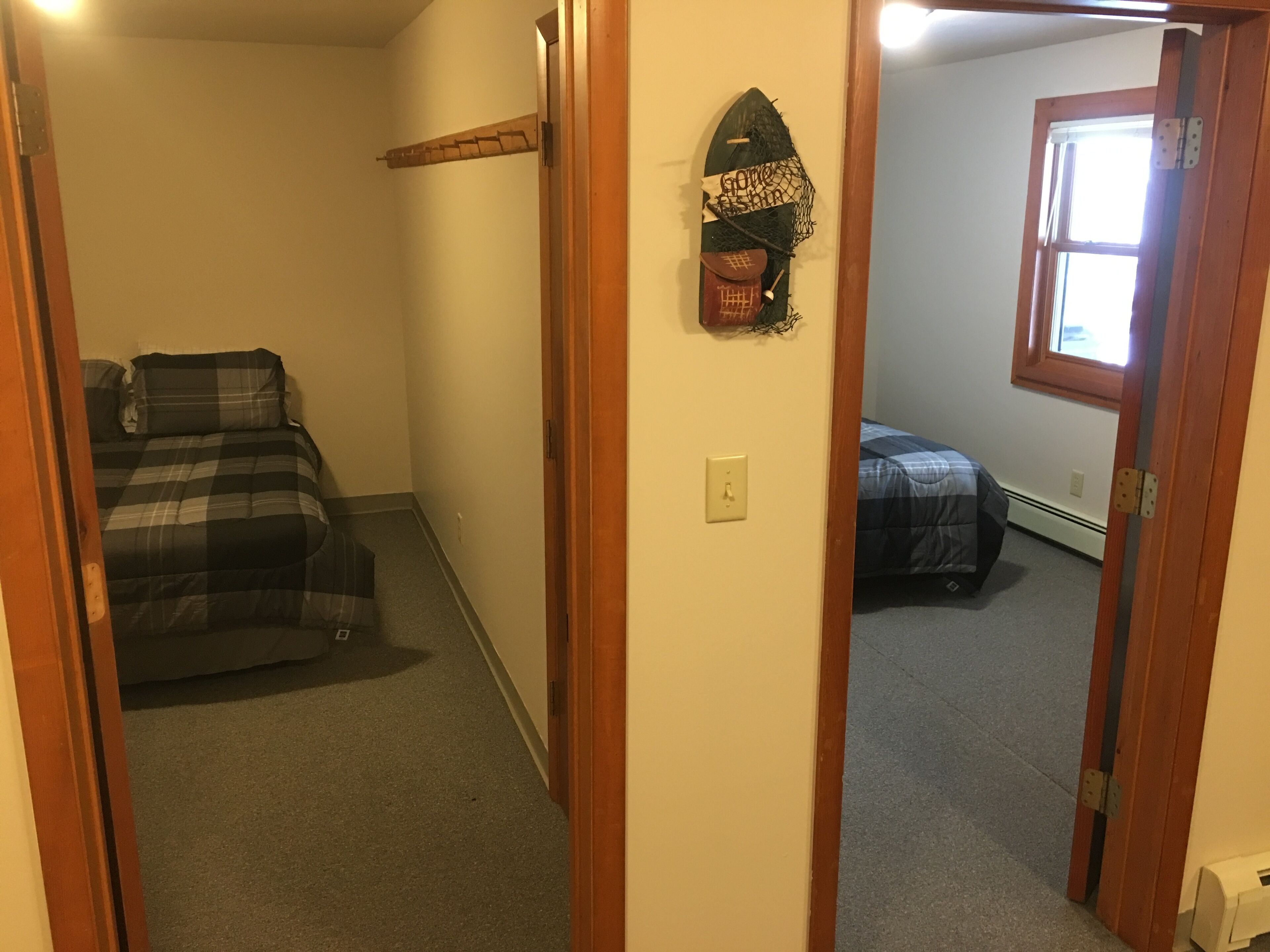 Une pièce comprenant un lit, une étagère fixée au mur avec divers objets, et une fenêtre.