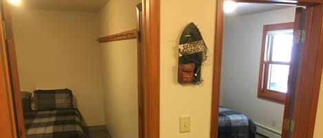 Une pièce comprenant un lit, une étagère fixée au mur avec divers objets, et une fenêtre.
