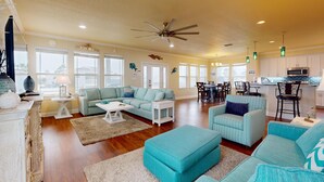 A spacious living room with a large sofa, a dining area with a table and chairs, and a kitchen area with cabinets and a microwave. - Luxury Home Detached Suite, Private Pool, Located Near Beach (Port Aransas)