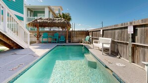 A swimming pool with a wooden deck, a thatched umbrella, and a wooden fence. - Luxury Home Detached Suite, Private Pool, Located Near Beach (Port Aransas)