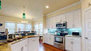 A spacious kitchen with white cabinets, a granite countertop, a stainless steel oven, and a microwave. - Luxury Home Detached Suite, Private Pool, Located Near Beach (Port Aransas)