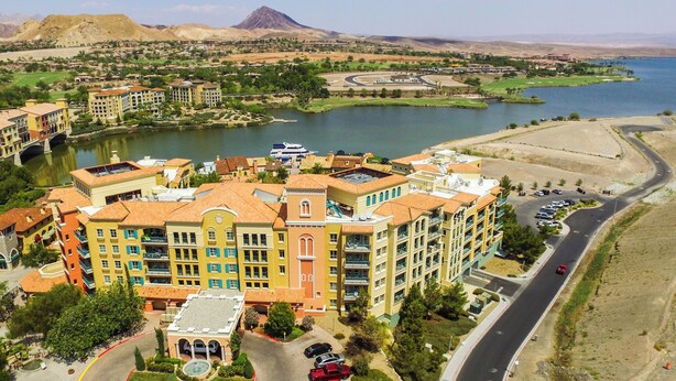 A multi-story hotel with balconies, a central courtyard, and a view of a lake and mountains. - Escape to Paradise: Luxe 2-Bedroom Retreat (Henderson)