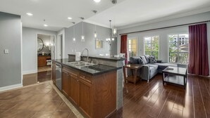 A modern kitchen with a central island, wooden cabinets, and a dining area with a sofa and table. - Escape to Paradise: Luxe 2-Bedroom Retreat (Henderson)