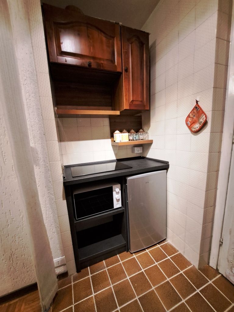 Une cuisine compacte avec des meubles en bois, un four encastré et un réfrigérateur en acier inoxydable.