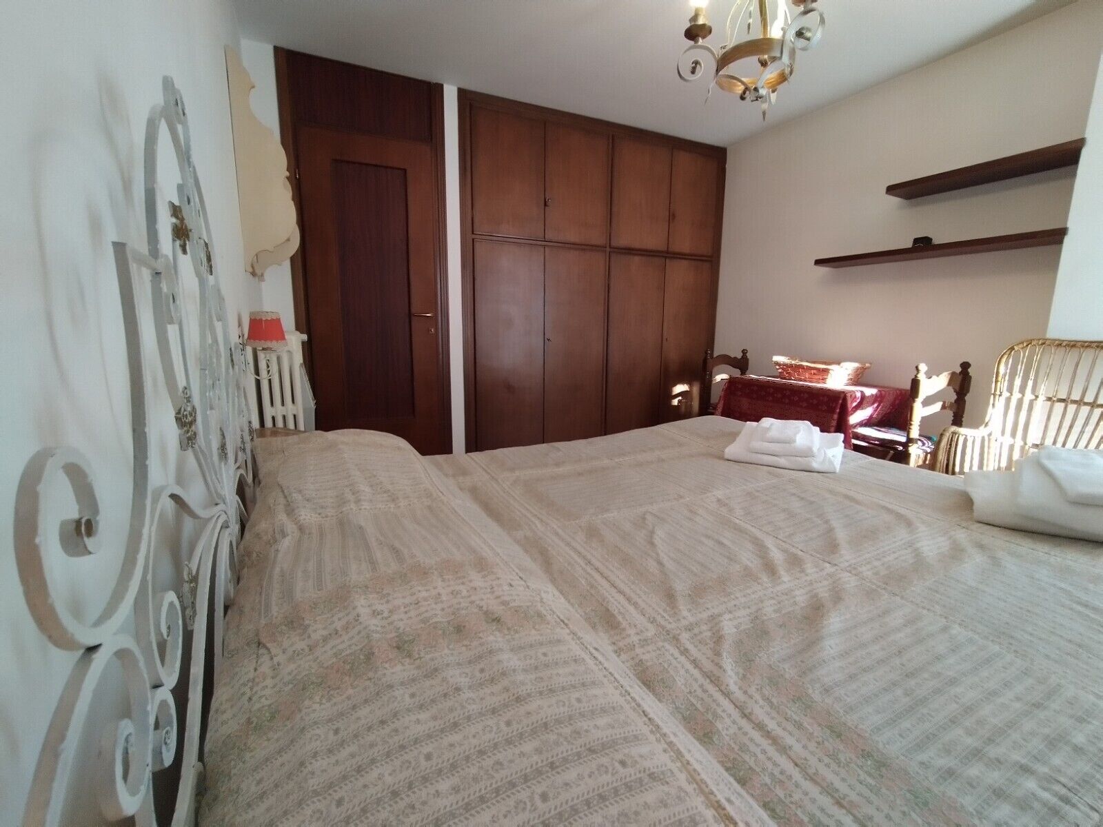 Une chambre à coucher avec un lit, une armoire, un lustre et une chaise.