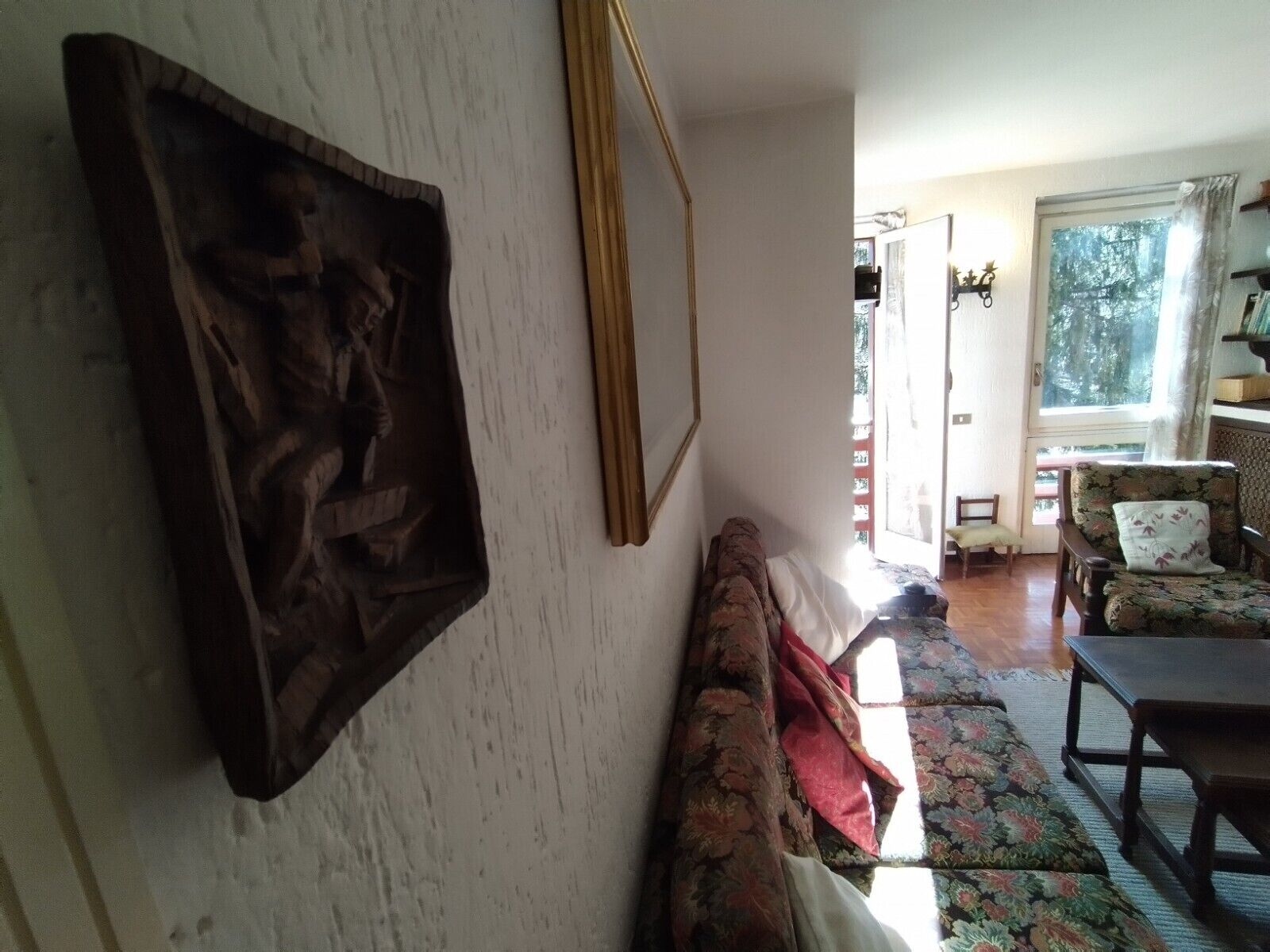 Ein Wohnzimmer mit einer Couch, einem Holzstuhl, einem Tisch und einem großen Fenster.