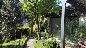 A garden pathway leading to a covered seating area with a table and chairs.