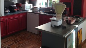 A kitchen with red cabinets, a stainless steel refrigerator, a microwave, and a coffee maker.
