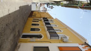 Un callejón estrecho flanqueado por edificios, con balcones que incluyen barandillas y unidades de aire acondicionado.
