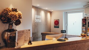 Mostrador de recepción de hotel con un jarrón de flores secas, un menú y un cartel que dice "hotel benai".