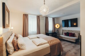 A hotel room with a bed, a sofa, a desk, a lamp, and a TV. - Berial (Düsseldorf)