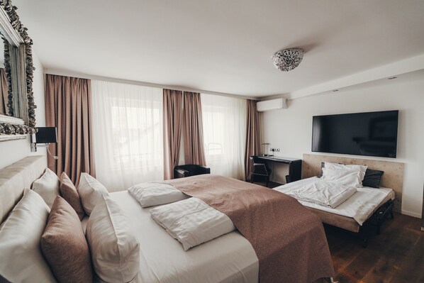 A hotel room with a large bed, a desk, a chair, a TV, and a window with curtains. - Berial (Düsseldorf)