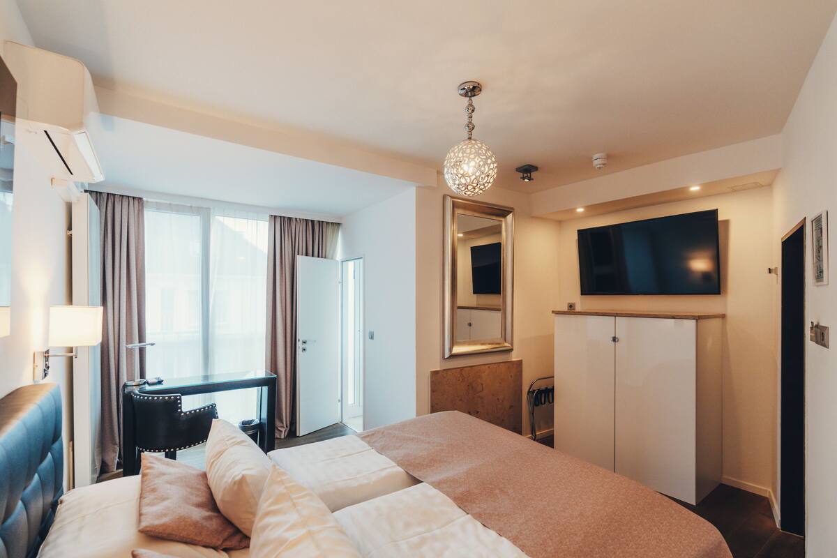 A hotel room with a bed, a desk, a TV, and a wardrobe.