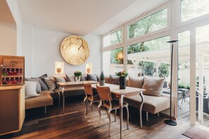 A modern interior with a wooden dining table, cushioned seating, and large windows offering a view of the outdoors. - Berial (Düsseldorf)