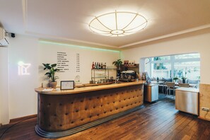A bar area with a wooden counter, a menu on the wall, and a seating area with a view of the outdoors. - Berial (Düsseldorf)