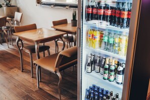 A restaurant interior with wooden tables and chairs, a refrigerator stocked with beverages, and a potted plant on the wall. - Berial (Düsseldorf)
