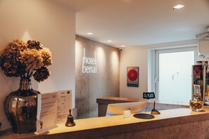 A hotel reception desk with a vase of dried flowers, a menu, and a sign that reads "hotel benai". - Berial (Düsseldorf)